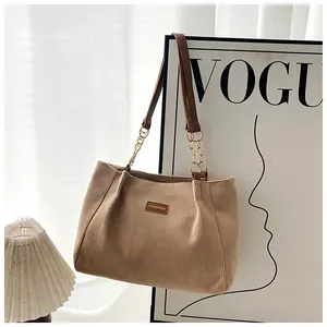 Detail of khaki corduroy tote bag showing leather FASHION label and chain handle