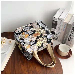 Detail van canvas draagtas met cartoon kattenprint, lederen label en zachte hengsels