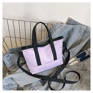 Détail du mini cabas en toile lavande avec sangles noires sur veste en jean