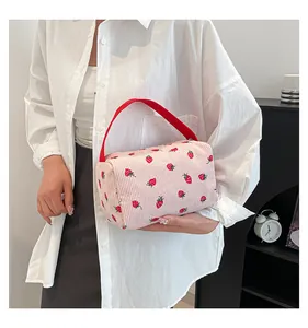 Close-up of pink corduroy storage bag with strawberry pattern and red handle detail