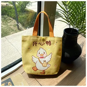 Detail of yellow canvas tote bag with cute cartoon duck illustration and snap closure