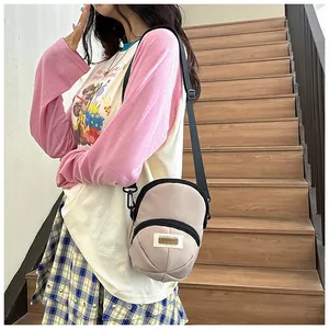 Detail of beige nylon crossbody bag featuring double zipper compartments and adjustable strap