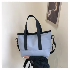 Détail du sac à bandoulière en toile bleu clair avec sangles noires et anneau en D en métal