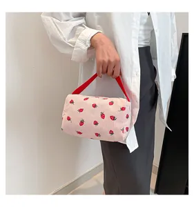 Detail of pink corduroy strawberry pouch featuring a red handle and soft texture