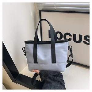 Détail du sac à bandoulière en toile bleu-gris clair avec poignées noires et sangle