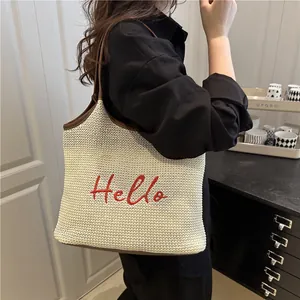 Straw woven tote bag with red Hello embroidery and brown leather straps for beach vacation