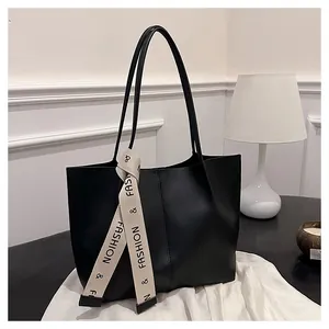 Detail shot of black leather tote bag featuring a decorative beige branded ribbon strap