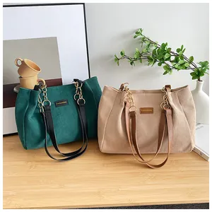 Detail view of corduroy tote bags in green and beige with metal chain straps