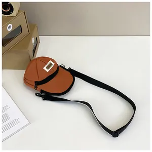 Close-up of a unique baseball cap shaped crossbody bag in orange with adjustable strap