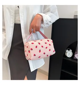 Close-up of strawberry print corduroy pouch held by model for daily lifestyle use
