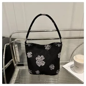 Detail of a black Chinese-style bucket bag with white floral embroidery and handle