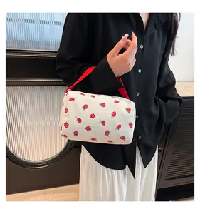 Detail of corduroy pouch with strawberry print and red handle carried by model