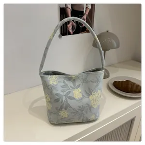 Detail of light blue floral bucket bag on a white table with minimalist lifestyle decor