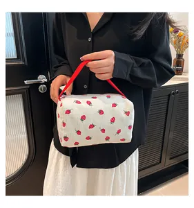 Detail of floral corduroy pouch featuring red strawberry prints and a woven handle