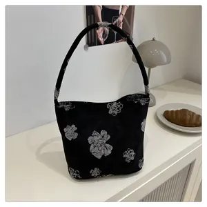 Detail of black floral canvas hobo bag with white flower patterns on a white table