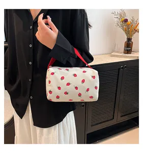 Close-up of hand-held strawberry floral corduroy pouch with red handle and zipper detail