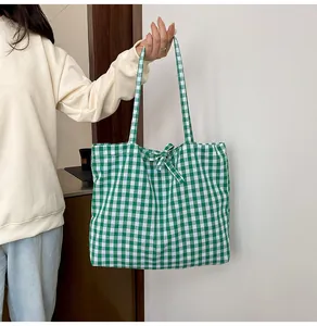 Detail of green and white gingham tote bag with a matching fabric bow and long strap