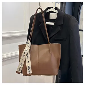 Detail of brown leather tote bag featuring fashion ribbon and elegant vertical stitching