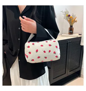 Detail of strawberry print corduroy pouch with wide strap handle in a lifestyle setting