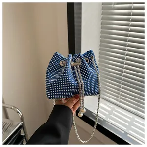 Detail van de blauwe strass emmertas met metalen trekkoord en parelhangers