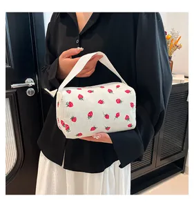 Detail of handheld corduroy storage bag with strawberry embroidery and soft woven handles