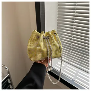 Detail van gele strass emmer tas met zilveren ketting en witte parel accenten