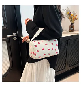 Detail of strawberry print corduroy pouch with white webbing handle and cylinder design
