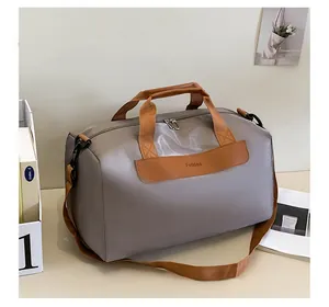 Détail du sac de sport en nylon imperméable gris avec poignées en cuir marron et logo