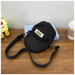 Detail of unique baseball cap shaped nylon crossbody bag with adjustable strap on wooden table