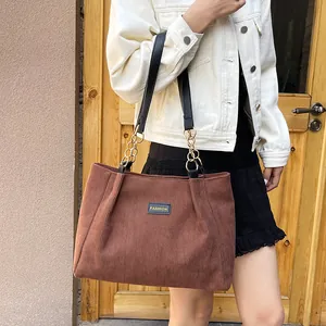 Brown corduroy tote bag with fashion patch and golden chain straps in a casual style