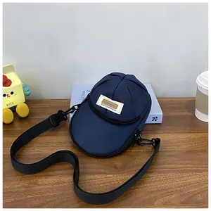 Detail of navy blue baseball cap shaped crossbody bag with vintage embroidery on wooden desk