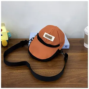 Detailed shot of an orange baseball cap shaped nylon crossbody bag on a wooden table