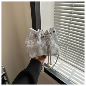 Detail van zilveren mini-emmertas met strass-steentjes, parelkoord en een metalen ketting