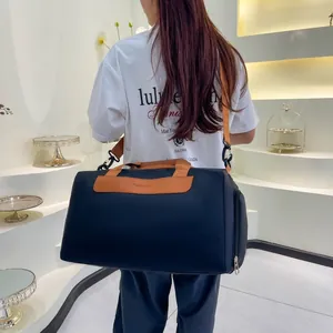 Vue détaillée du grand sac de sport bleu marine avec finitions brunes sur modèle