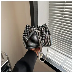 Detail van zwarte emmertas met gekleurde strassteentjes en metalen trekkoord met parelsier