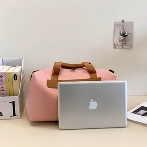 Détail du sac de sport rose avec poignées marron et ordinateur montrant sa capacité