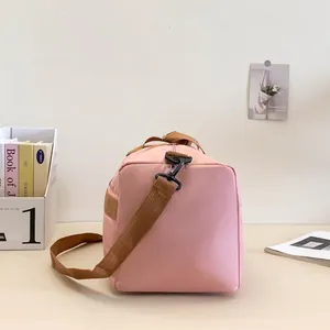 Vue détaillée du sac de sport rose montrant la sangle en nylon et les crochets en métal