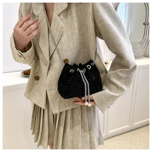 Detail van zwarte strass emmer tas met zilveren ketting en witte parel trekkoord bedels