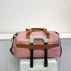 Sac de sport rose avec passant pour valise montré sur une poignée de bagage blanc