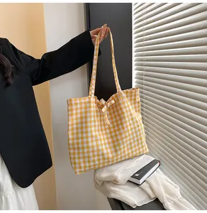Detail of yellow gingham fabric tote bag with a decorative bow and long shoulder straps