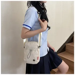 Détail du sac bandoulière en nylon beige avec étiquette mode et tissu texturé