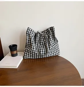 Detailed close-up of a black and white checkered tote bag on a wooden table surface