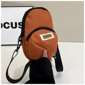 Detail of an orange baseball cap shaped crossbody phone bag with adjustable strap