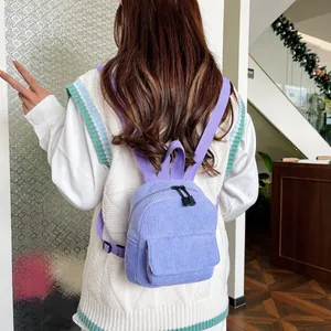 Rear view of a model wearing a mini purple corduroy backpack with adjustable straps