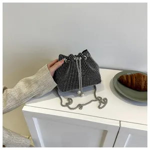 Detail van zwarte emmertas met zilveren strass, trekkoord en parel accenten vallen