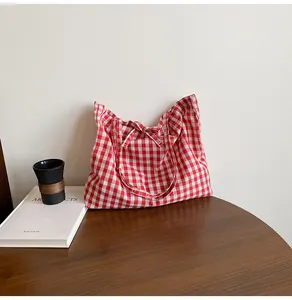 Detail of red and white gingham fabric tote bag with a decorative bow on a wooden table