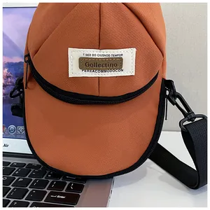 Detailed shot of hat-shaped orange nylon crossbody bag with adjustable black strap