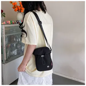 Vue latérale d'un petit sac bandoulière en toile noire avec sangle réglable pour femme