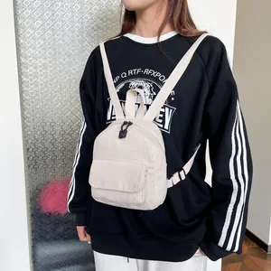 Mini cream corduroy backpack shown on model with adjustable straps and front pocket