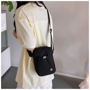 Détail du sac bandoulière noir minimaliste avec cordon argenté et petite étiquette